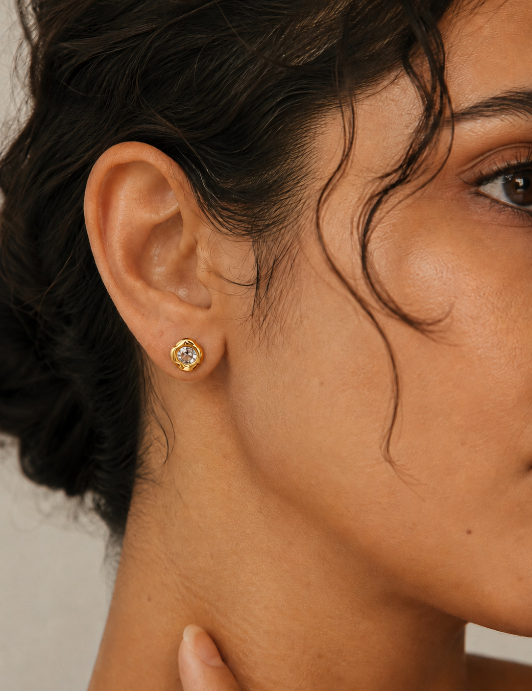 Model wearing the Halo Stud — a round cubic zirconia set in an organic molten-edge 18K gold bezel — Zoé Jewelry.
