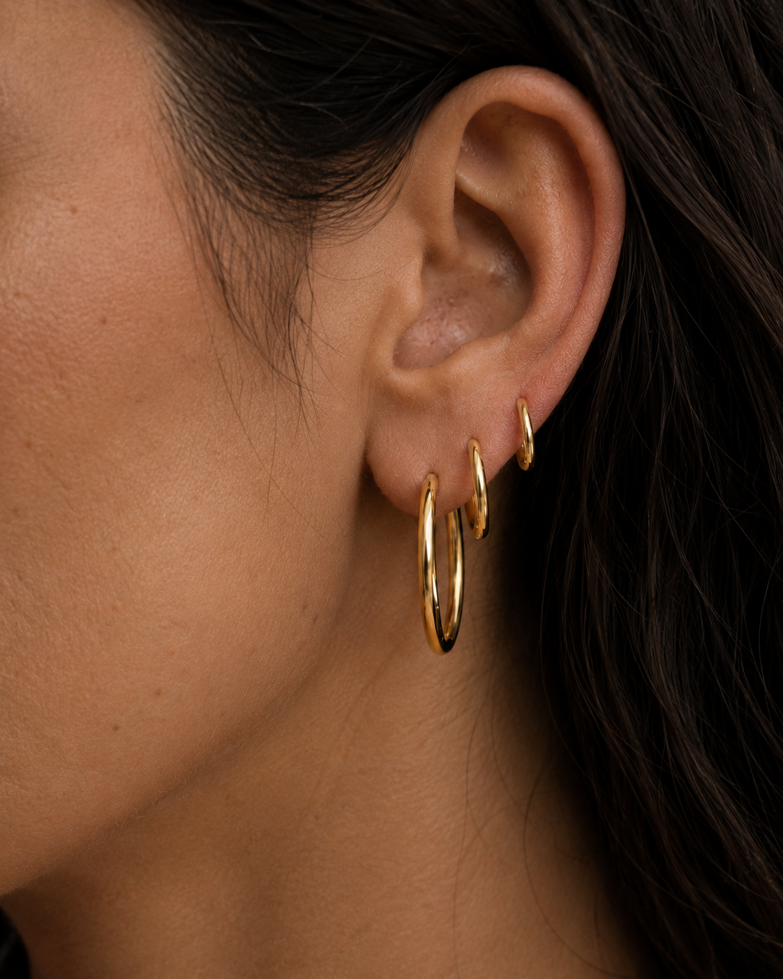 Model wearing Classic Hoops in small, medium, and large stacked up the ear — slim 18K gold hoops that step up in size — Zoé Jewelry