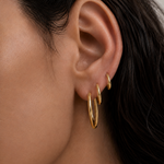 Model wearing Classic Hoops in small, medium, and large stacked up the ear — slim 18K gold hoops that step up in size — Zoé Jewelry