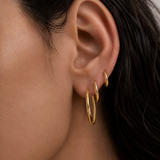 Model wearing Classic Hoops in small, medium, and large stacked up the ear — slim 18K gold hoops that step up in size — Zoé Jewelry