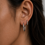 Model wearing Classic Silver Hoops in small and medium stacked on the ear — slim rhodium-plated silver hoops from Zoé Jewelry.