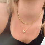 Model wearing Dua paperclip and CZ tennis necklace in 18K gold-plated finish at the collarbone