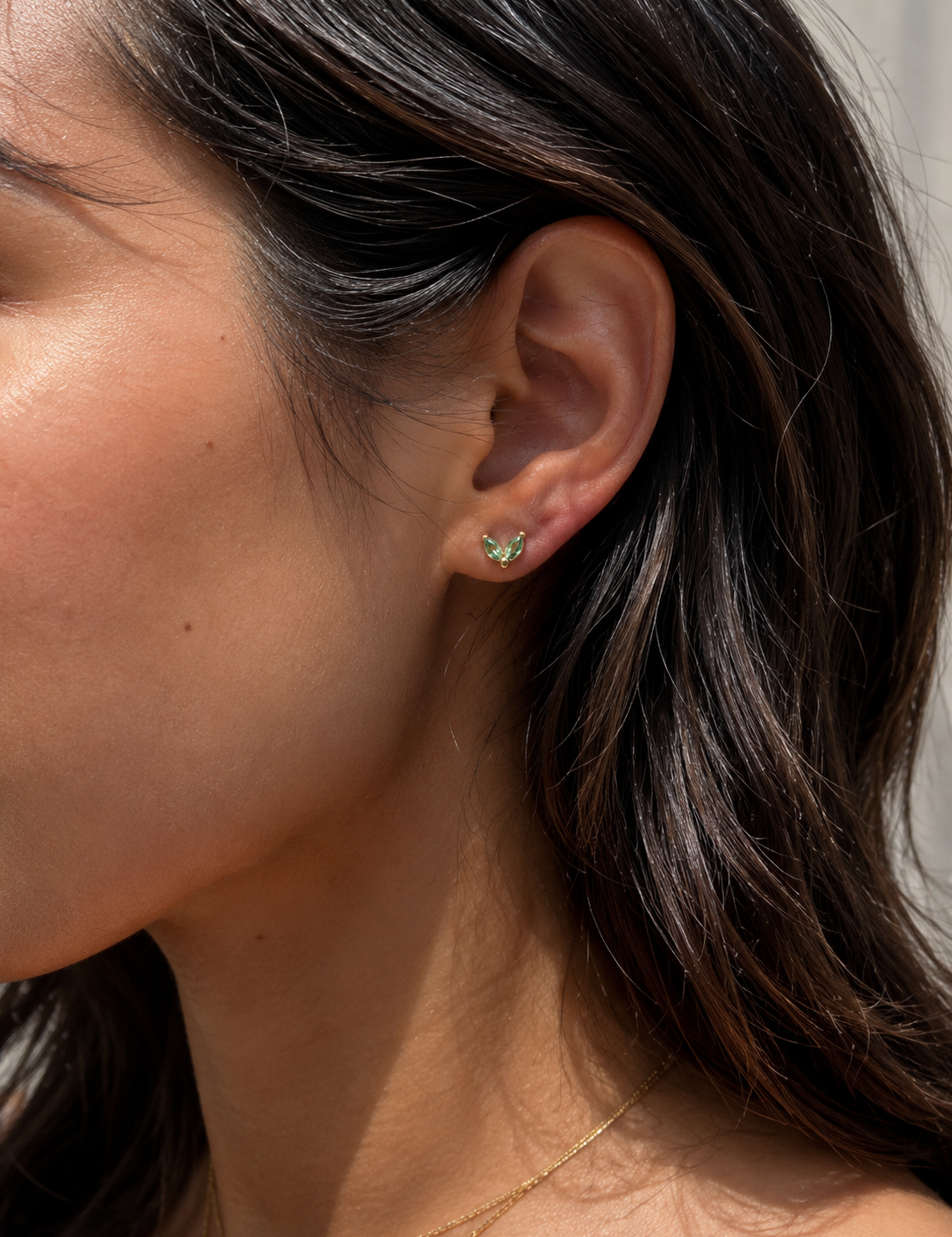 Model wearing the Ember Studs — dainty petal-shaped gold studs with a green stone — Zoé Jewelry.