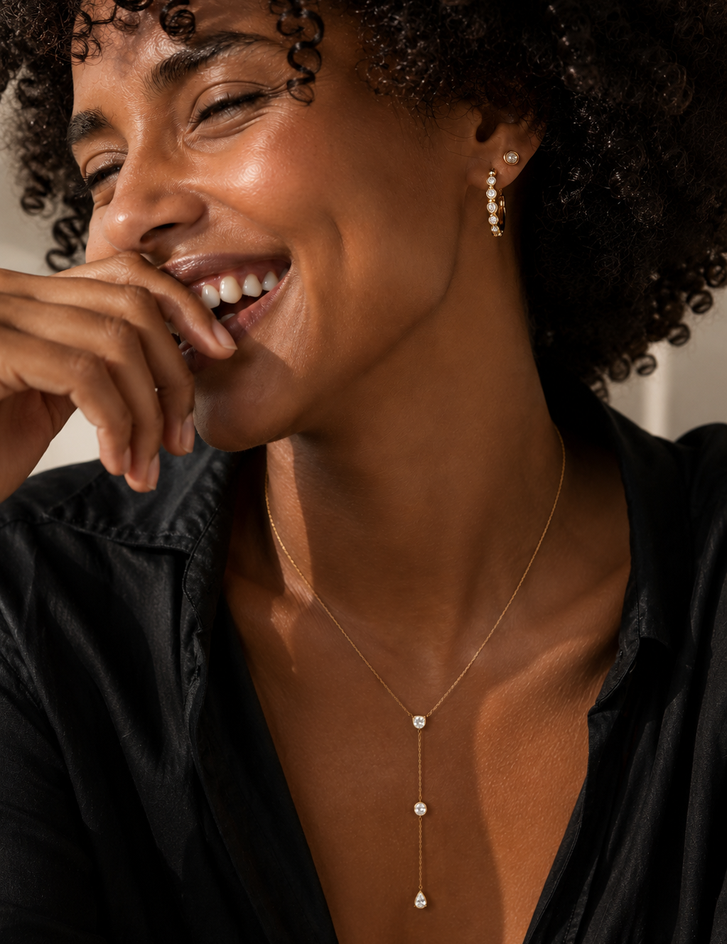 Model wearing the Eternity Huggie — bezel-set CZ 18K gold huggie hoops styled with a gold stud — Zoé Jewelry.