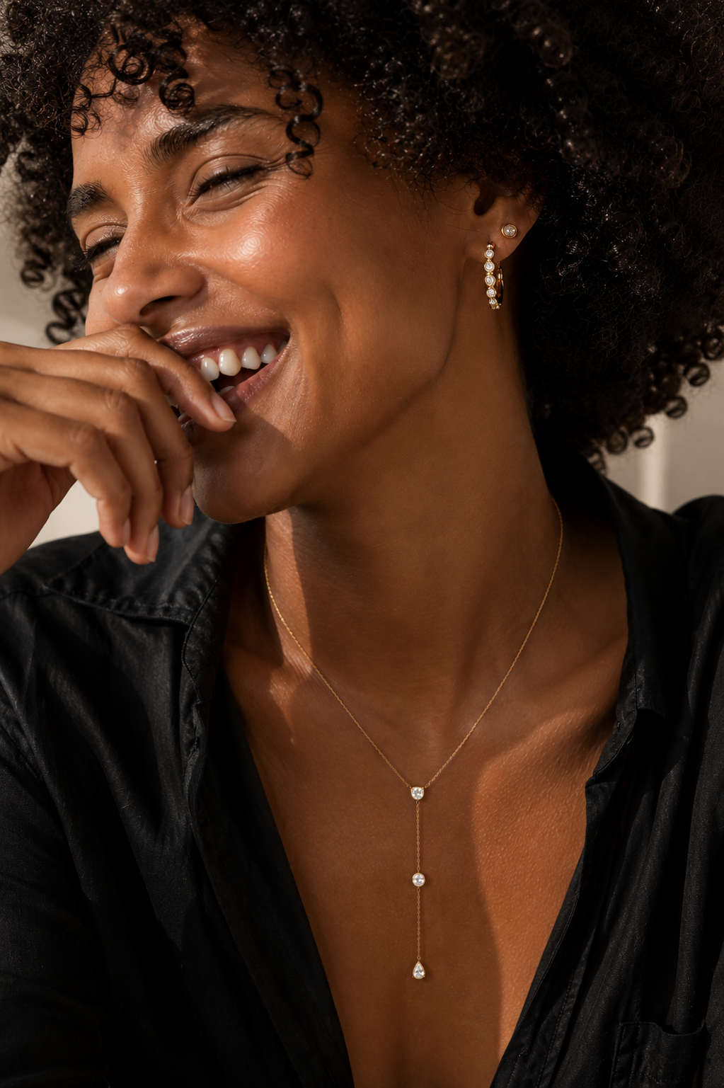Model wearing the Eternity Huggie — bezel-set CZ 18K gold huggie hoops styled with a gold stud — Zoé Jewelry.