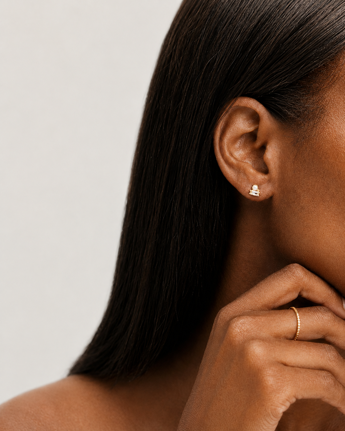 Model wearing the Odette Stud — a gold stud pairing a button pearl with a baguette-cut cubic zirconia — Zoé Jewelry.