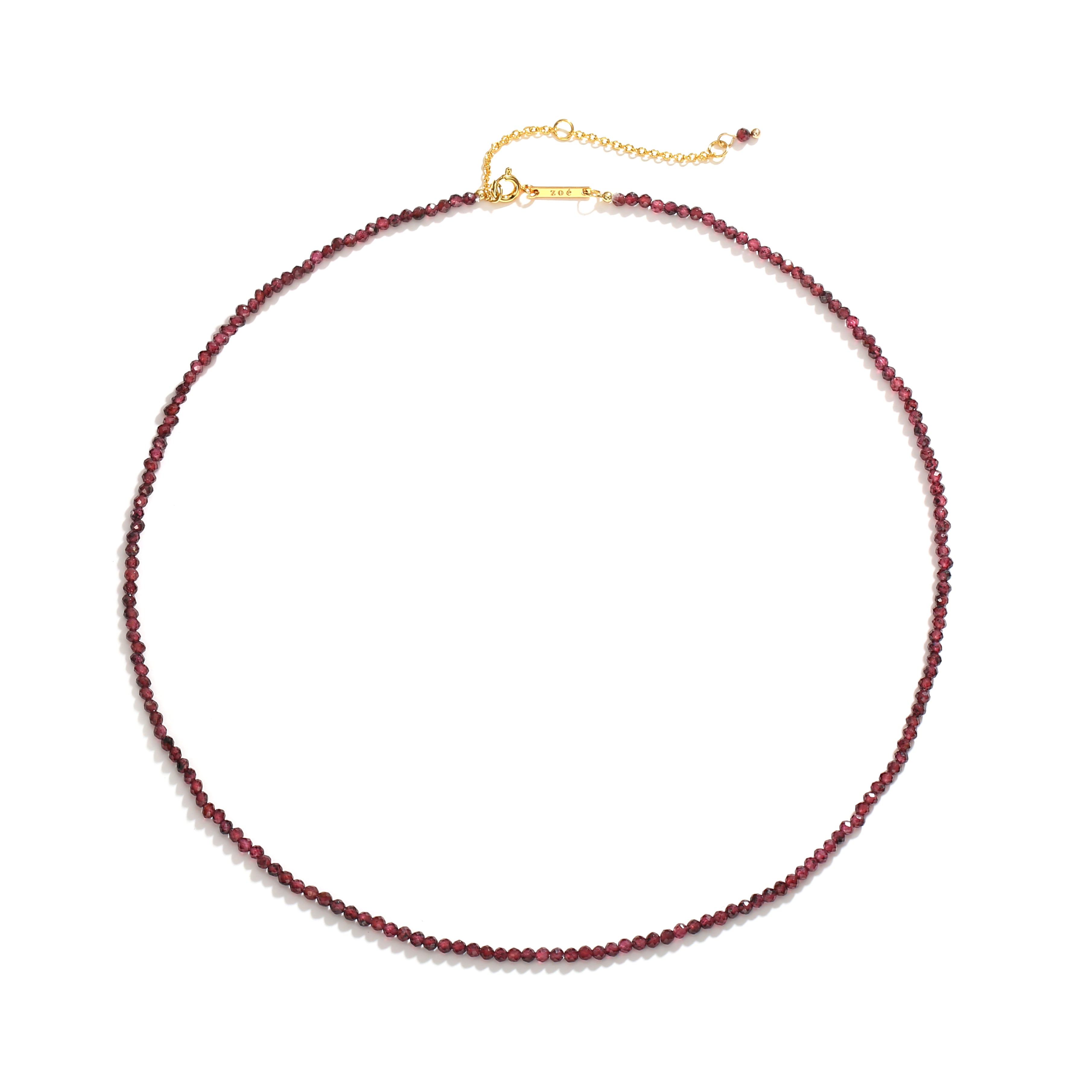 Dainty necklace of small deep red faceted gemstone beads on a fine strand with clasp and Zoé tag, on white background.