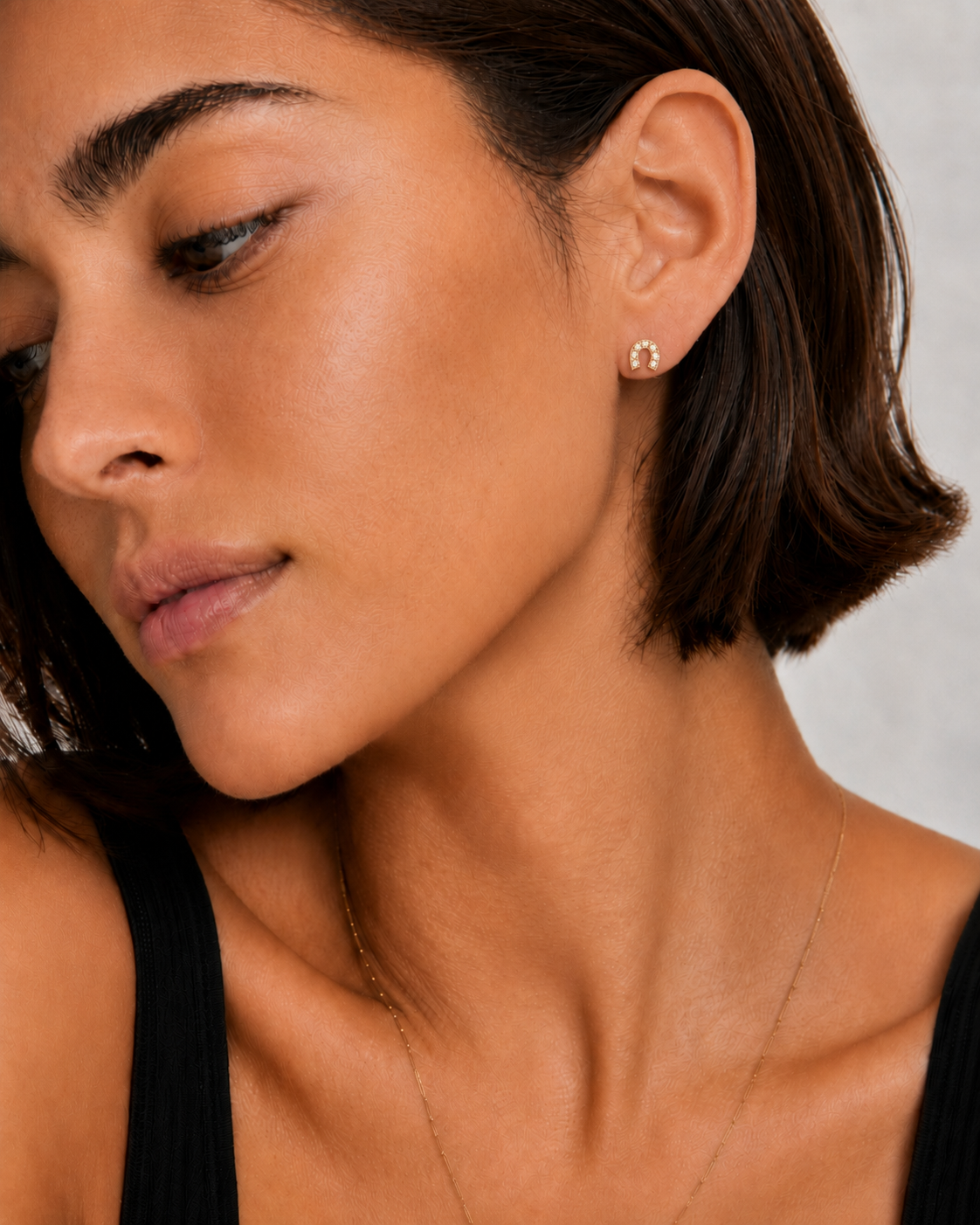 Model wearing the Saddle Up Studs — a tiny 18K gold horseshoe stud with pavé CZ — Zoé Jewelry.