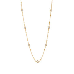 Stellar CZ station necklace with seven bezel-set stones on a beaded gold chain