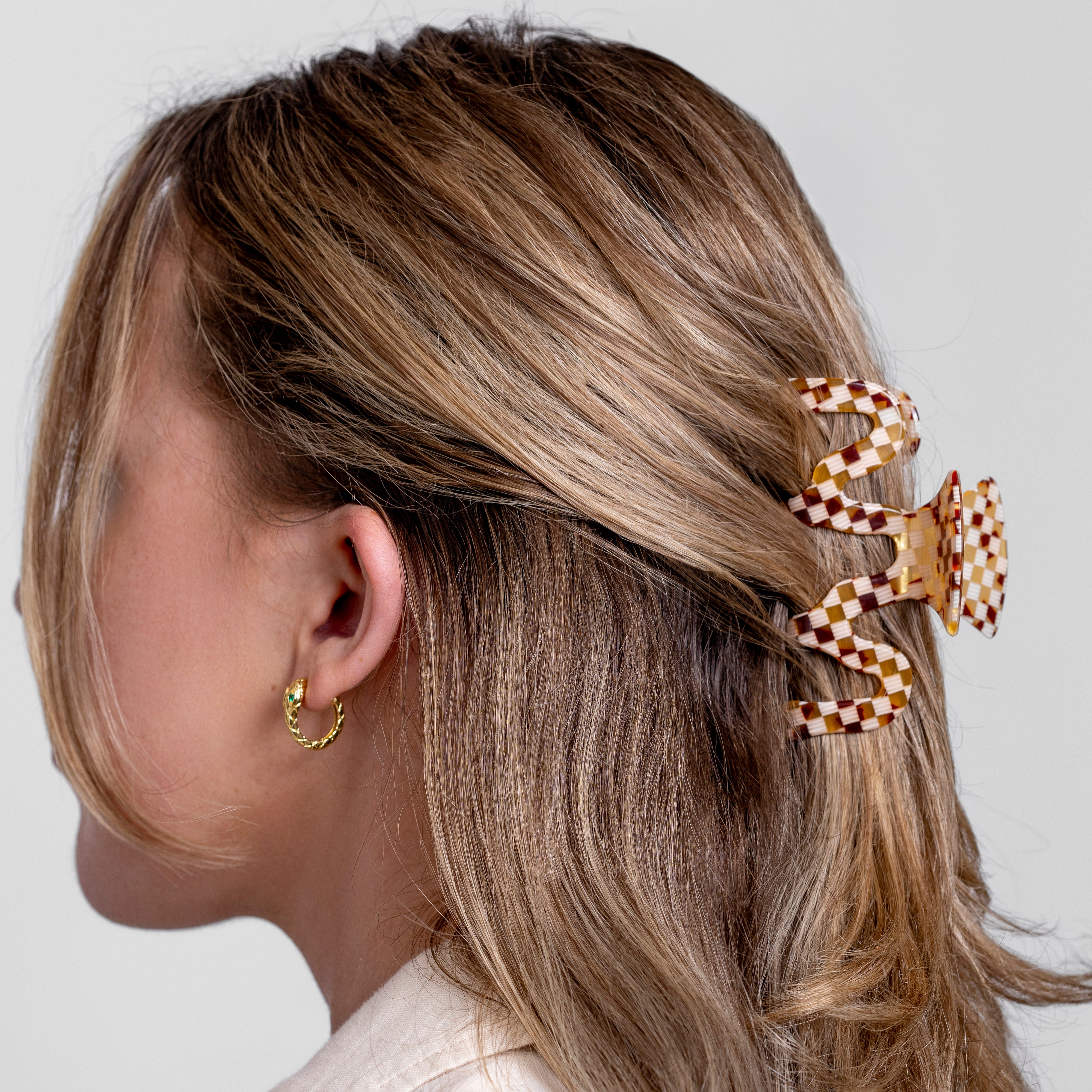 Model wearing Swiggle checkerboard claw clip in cellulose acetate at the back of the head
