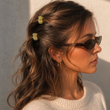 Model wearing two Thea Mini Clips in Citrus in half-up waves — bright yellow marbled acetate claw clips from Zoé Jewelry.