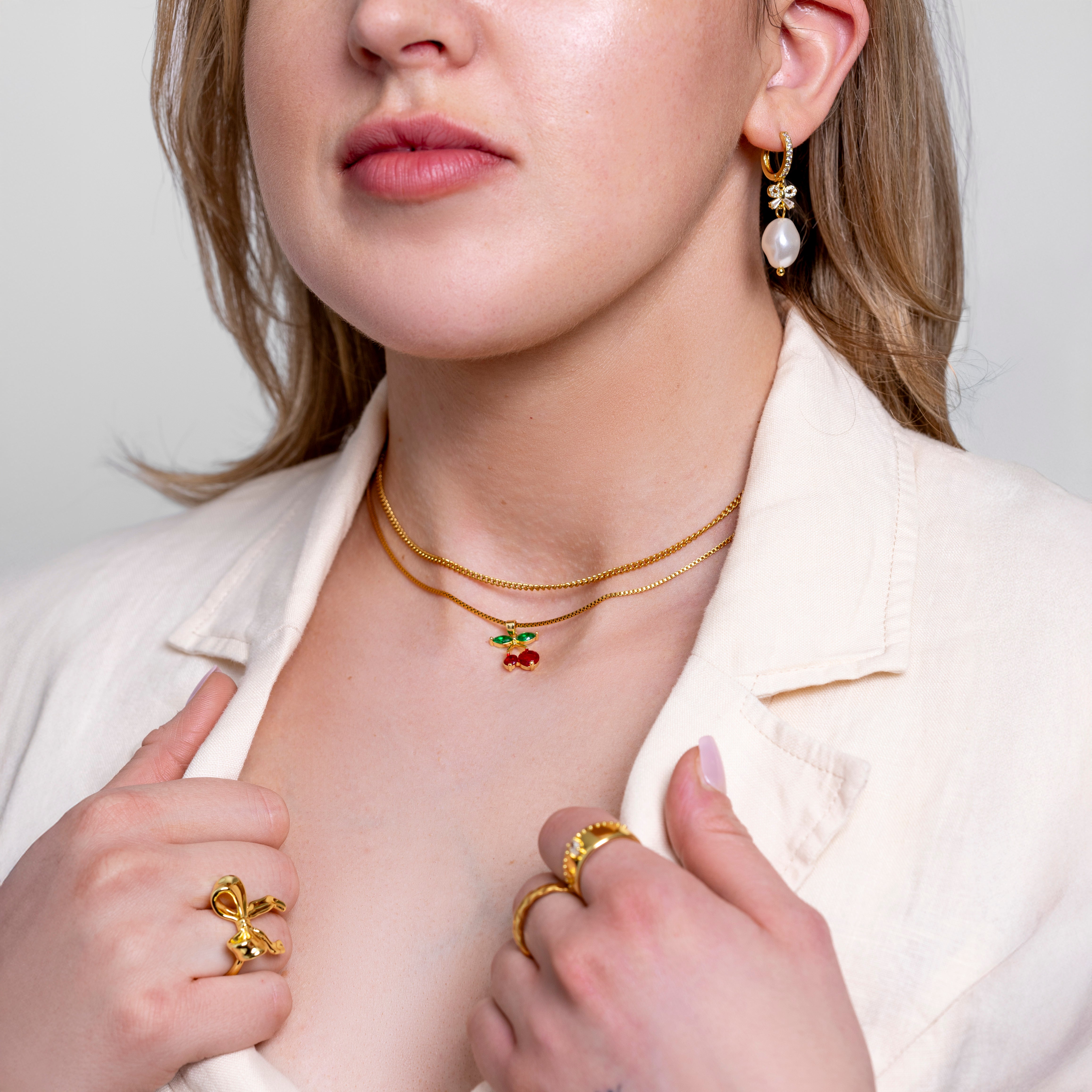 Model wearing Theo fine cable chain necklace in 18K gold-plated finish at the collarbone