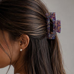 Model wearing Victoria rectangular claw clip in Lavender Latte marble cellulose acetate, close-up side view