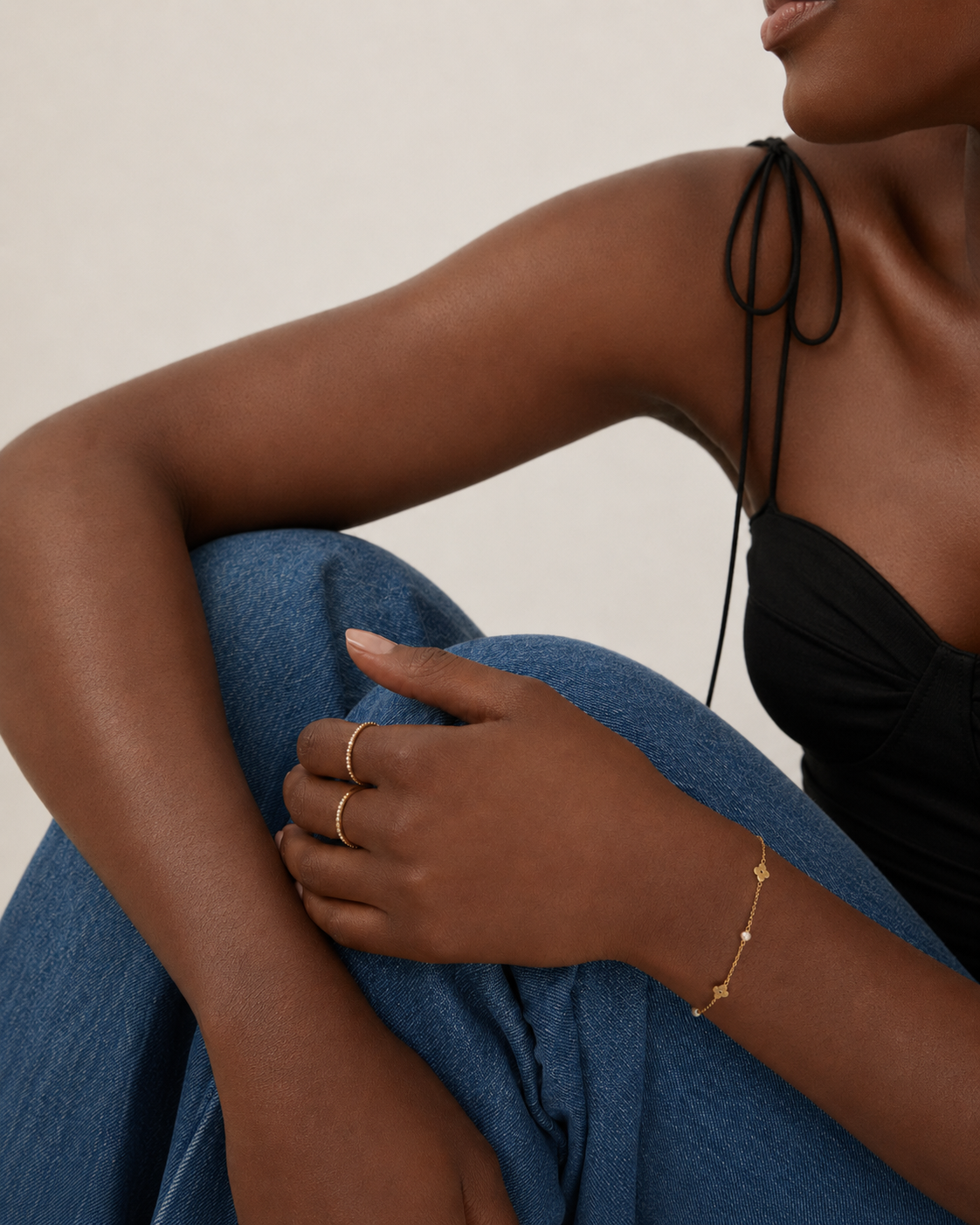 Model wearing a dainty gold chain bracelet with flower stations and pearl accents on the wrist, in 18k gold plating, soft natural light.