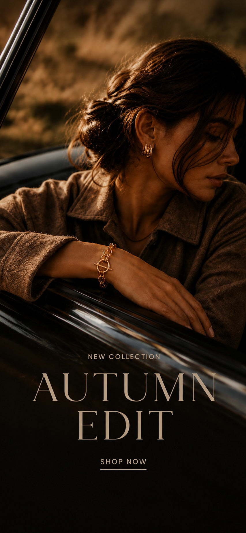  Woman in a wool coat wearing layered Zoé gold jewelry — chunky hoops, an oval pendant necklace, and a charm bracelet — for the Autumn Edit collection.