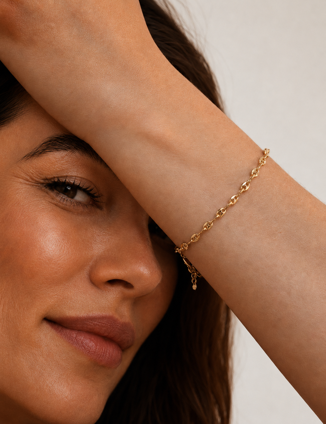 Model wearing a gold mariner-link chain bracelet with puffed coffee-bean links on the wrist, in 18k gold plating, soft warm natural light.