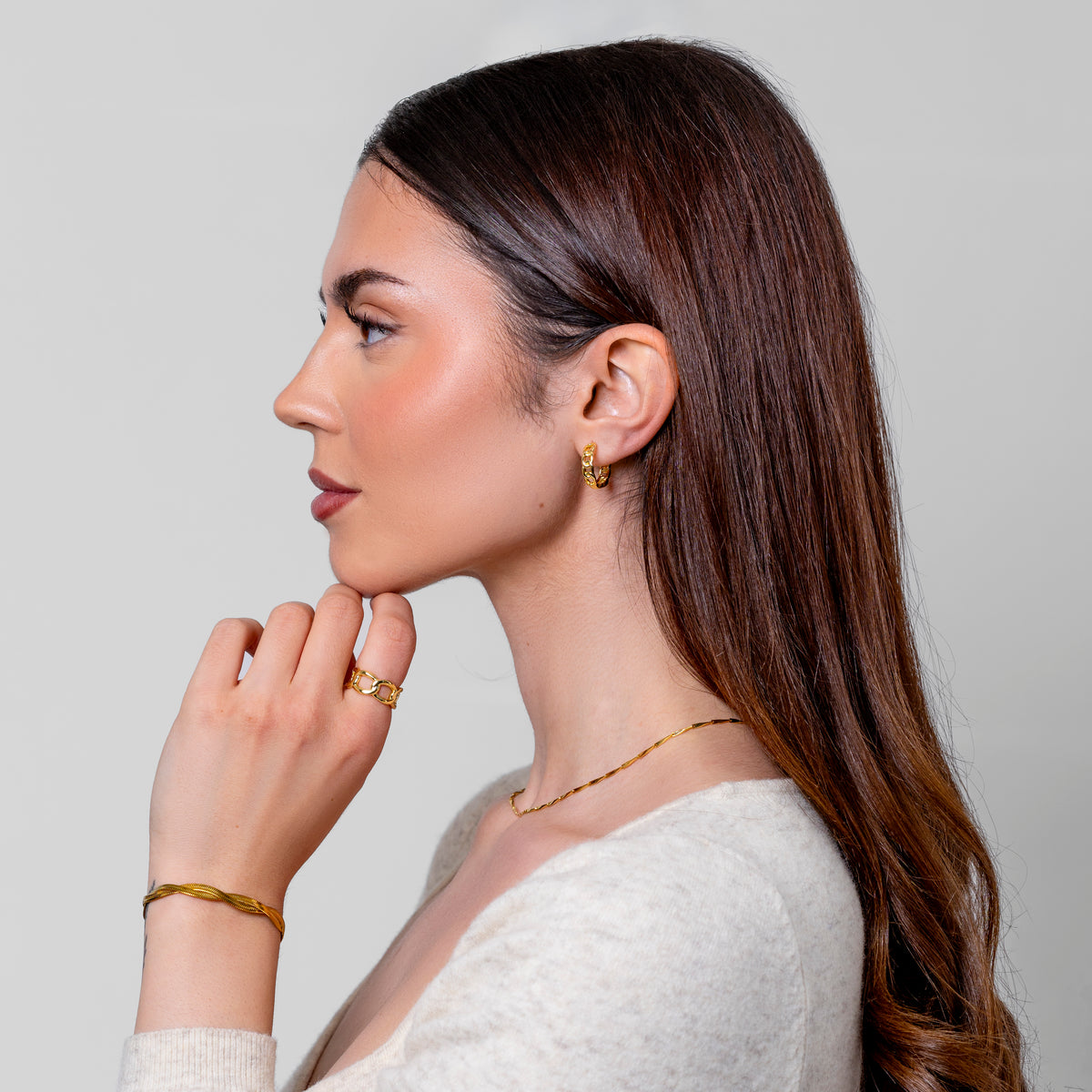 Woman wearing gold earrings, necklace, ring and bracelet from Zoé Jewelry