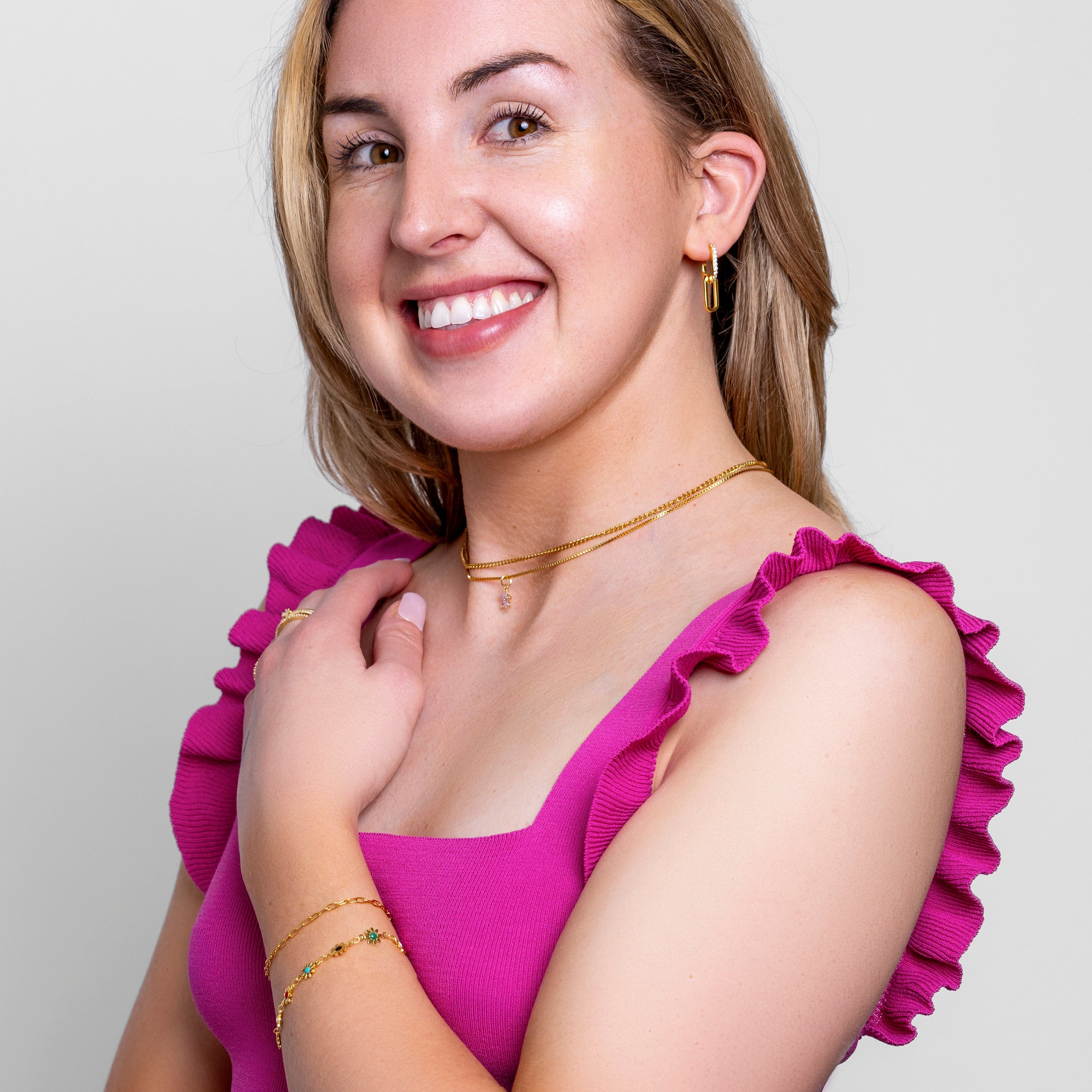 Model wearing a delicate fine gold paperclip chain bracelet on the wrist, in 18k gold plating, soft natural light.