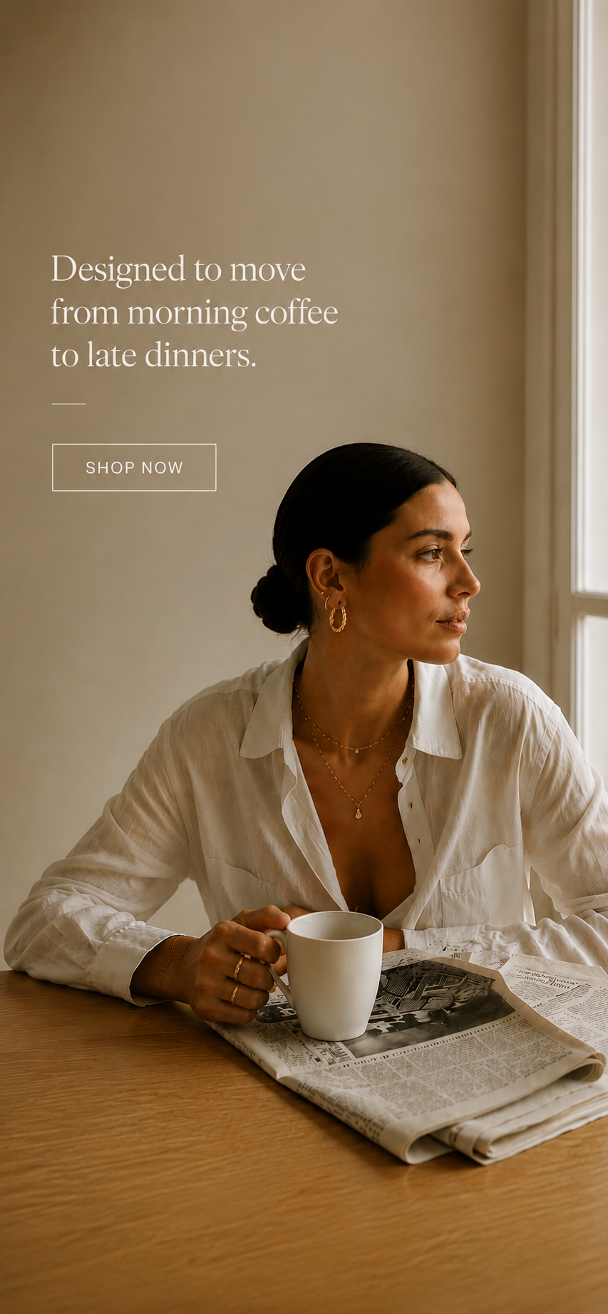 Woman in a white linen shirt wearing Zoé gold hoops and layered necklaces over morning coffee — everyday luxury jewelry.
