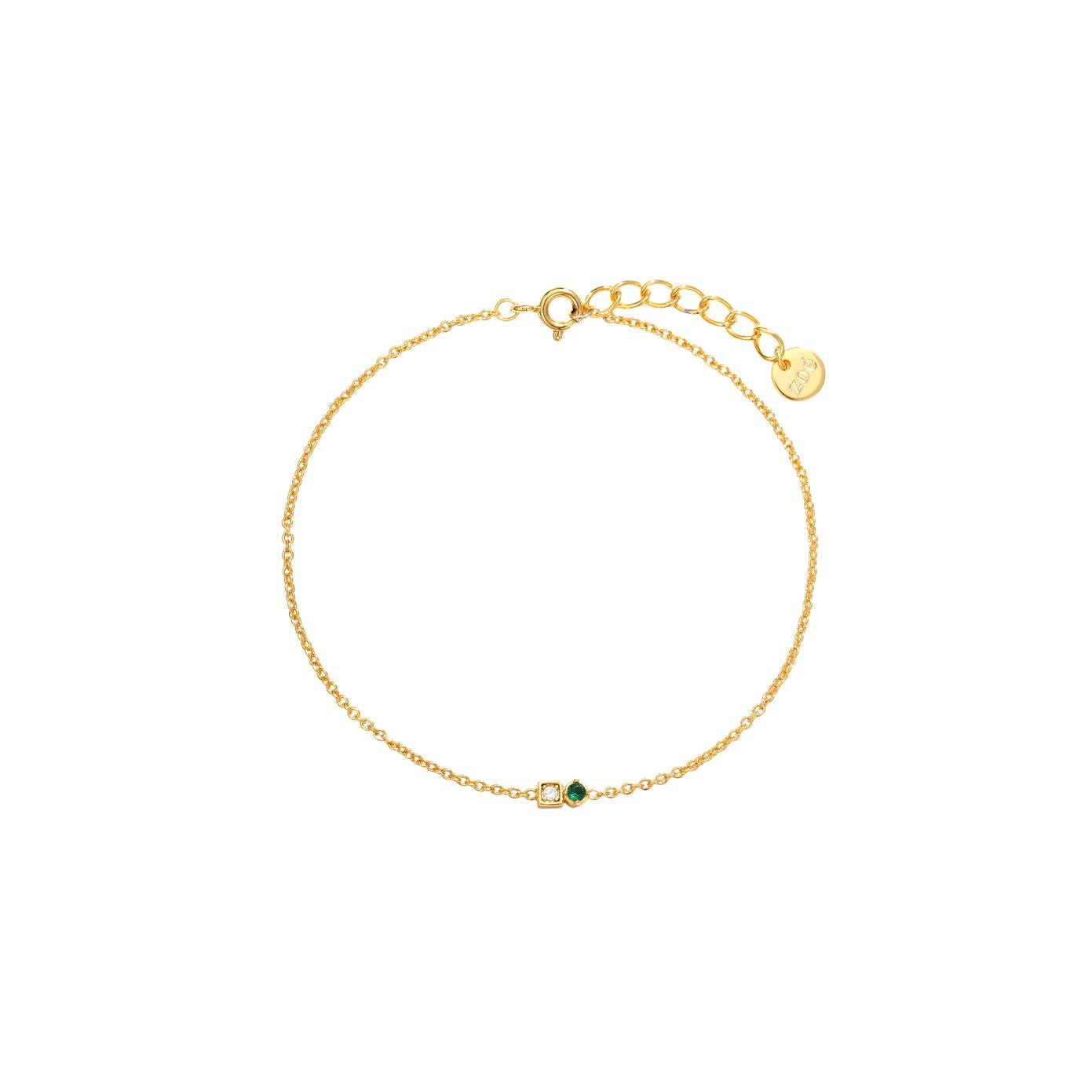 Dainty gold cable chain bracelet with a clear and green cubic zirconia two-stone detail, spring-ring clasp, adjustable extender, and Zoé disc tag, 18k gold plating.