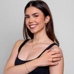 Model wearing a dainty gold oval-bead chain bracelet on the wrist, in 18k gold plating, soft natural light.