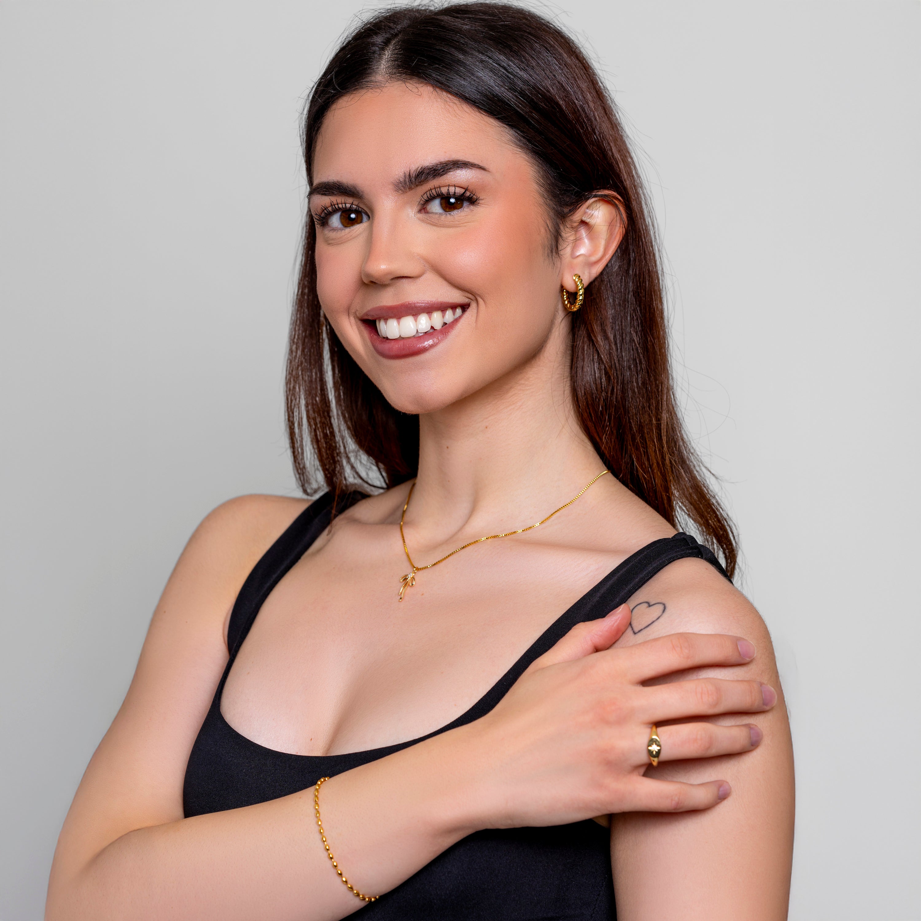 Model wearing a dainty gold oval-bead chain bracelet on the wrist, in 18k gold plating, soft natural light.