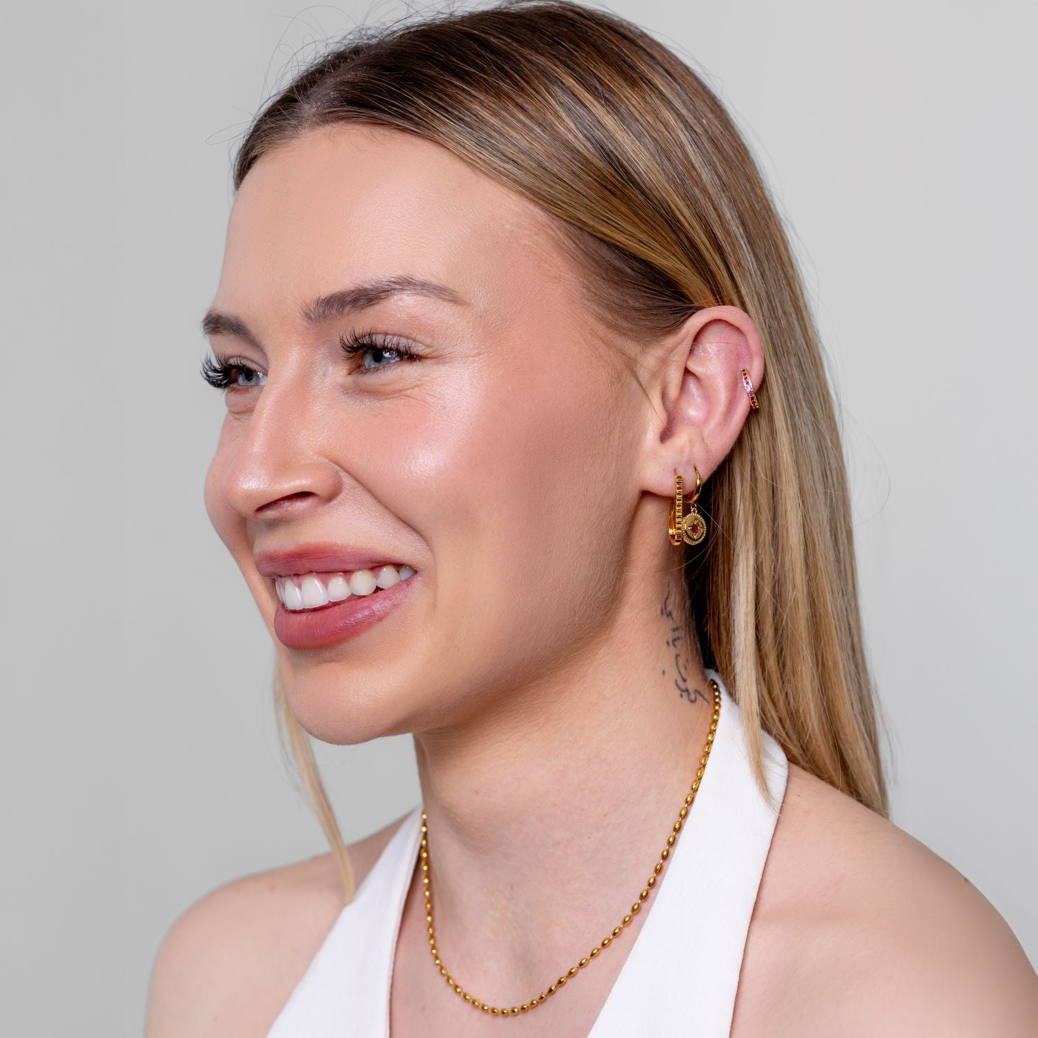 Model wearing a dainty gold oval-bead chain necklace at the neck, in 18k gold plating.