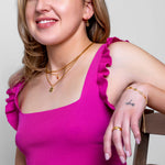 Model wearing a dainty gold oval-bead chain necklace at the neck, in 18k gold plating.