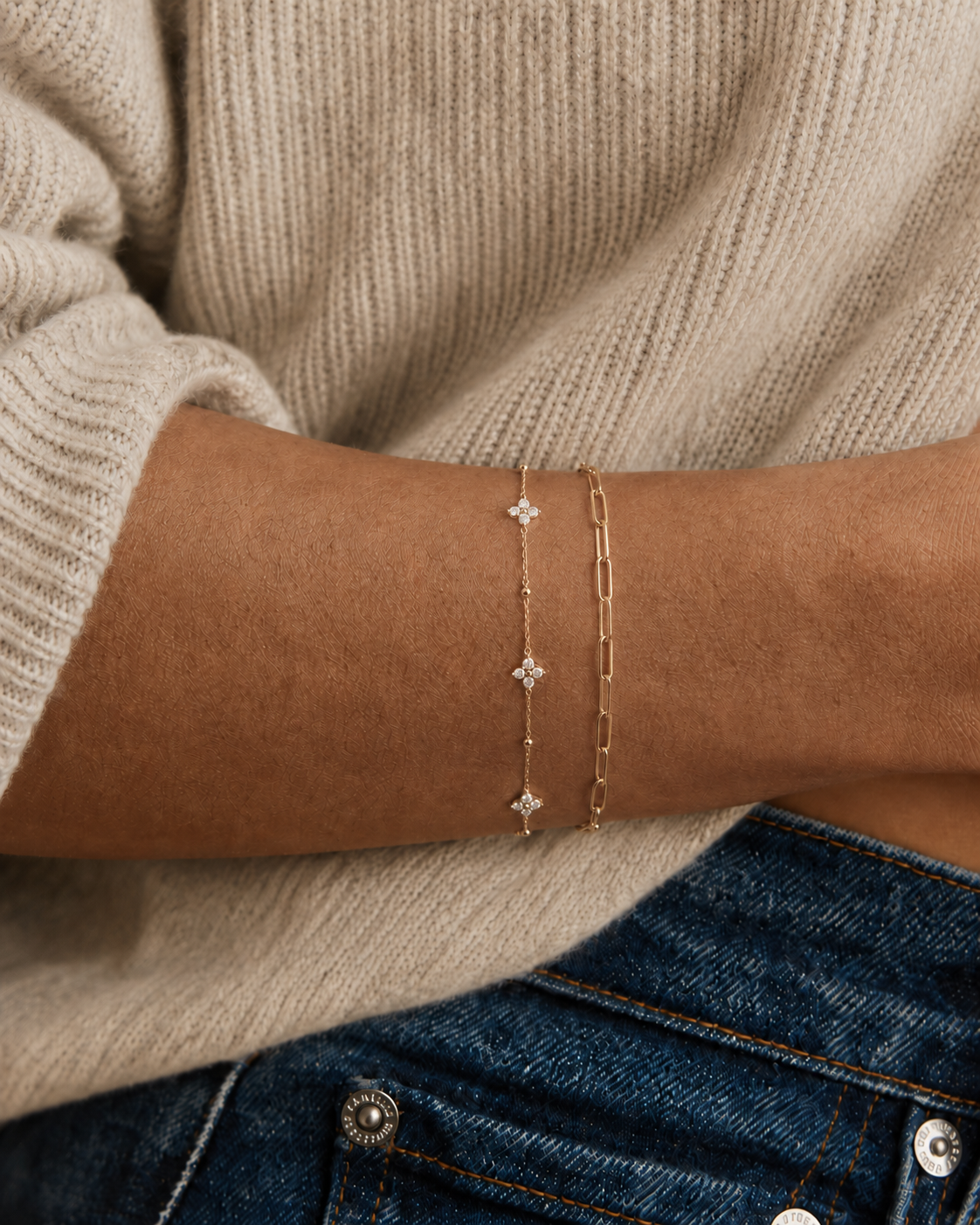 Model wearing a gold paperclip chain bracelet on the wrist, in 18k gold plating, soft natural light.