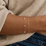 Model wearing a gold paperclip chain bracelet on the wrist, in 18k gold plating, soft natural light.