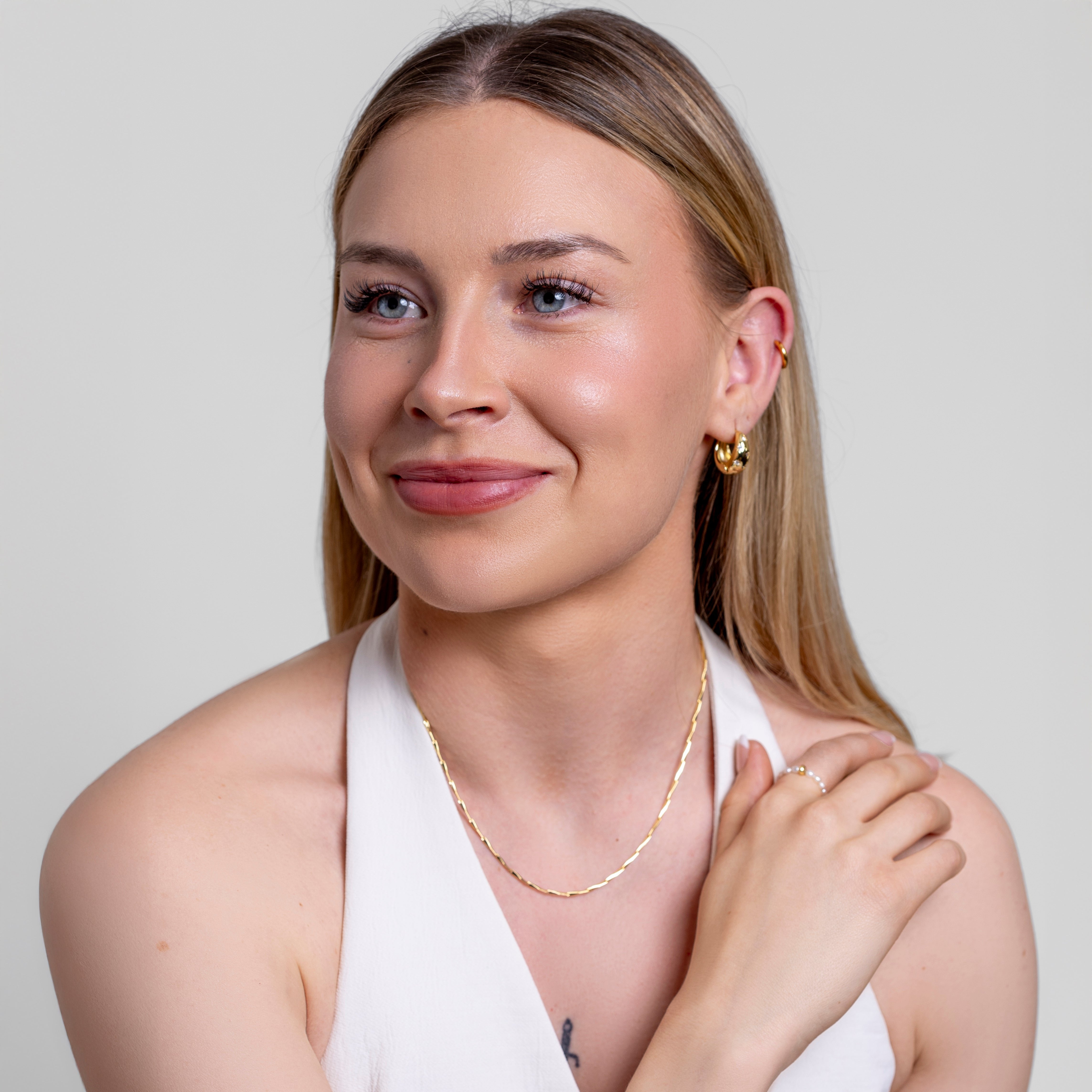 Model wearing a fine twisted gold chain necklace at the neck, in 18k gold plating.