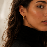 Model wearing chunky gold twisted double-strand hoop earrings on the ear, 18k gold plating.