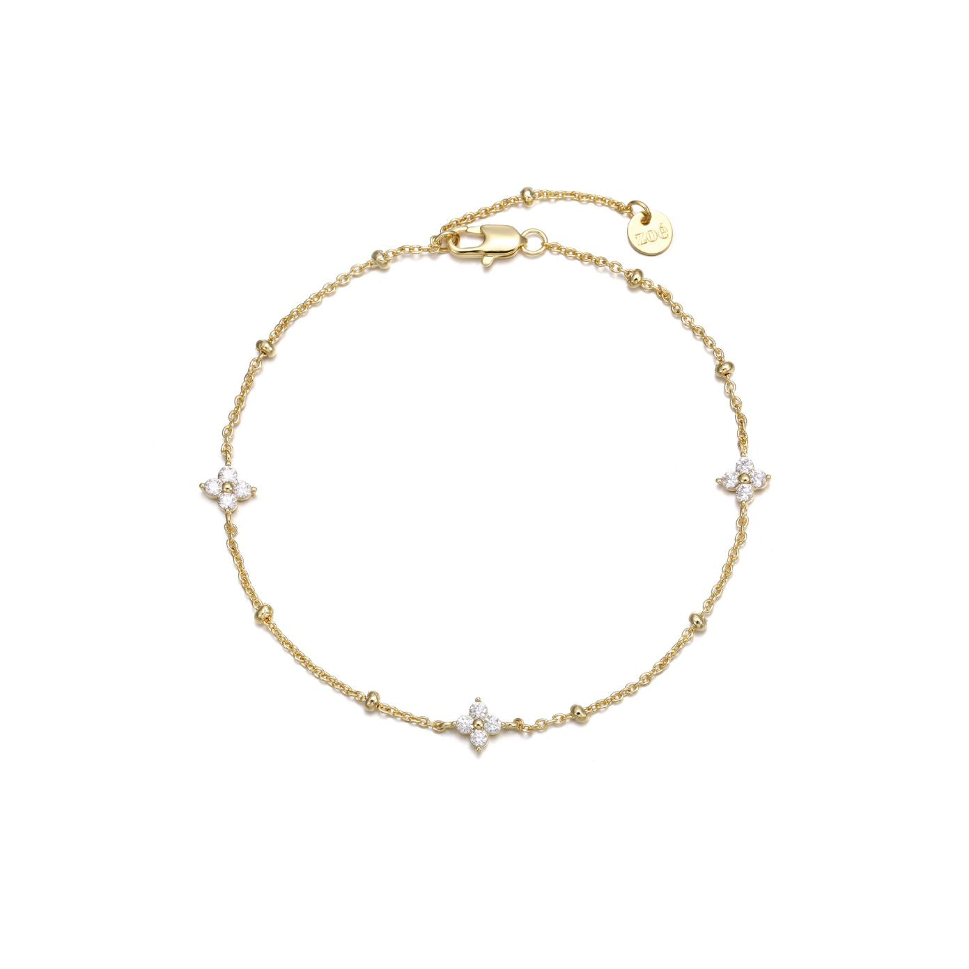 Dainty gold beaded cable chain bracelet with three cubic zirconia four-petal flower stations, lobster clasp, adjustable extender, and Zoé disc tag, in 18k gold plating.
